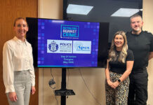 Members from Retailers Against Crime and Police Scotland stand around a TV screen to mark the Day of Action Glasgow May 2025.