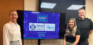 Members from Retailers Against Crime and Police Scotland stand around a TV screen to mark the Day of Action Glasgow May 2025.