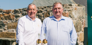 Saltire Rare Malt Founders Nigel Heywood and Keith Rennie (left to right) stand behind a whisky barrel with two whisky bottles on top of the barrel and a nosing glass in front of the whisky bottles.