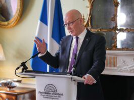 ScotGov sets out pledge to stamp out retail crime John Swinney, first minister of Scotland, stands at a white podium in Bute House during a press conference.