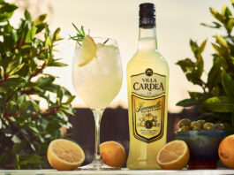 Villa Cardea Limoncello rolls out across Morrisons stores A bottle of Villa Cardea stands next to a wine glass with a Villa Cardea Limoncello Spritz cocktail in it with greenery in the background with oranges around the bottle and serve and a bowl of olives.
