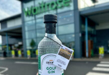 A person is holding a bottle of Eden Mill Golf Gin in front of a Waitrose supermarket store.