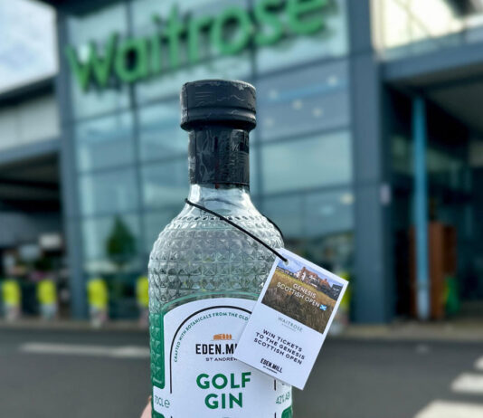 Eden Mill secures first UK-wide listing in Waitrose A person is holding a bottle of Eden Mill Golf Gin in front of a Waitrose supermarket store.