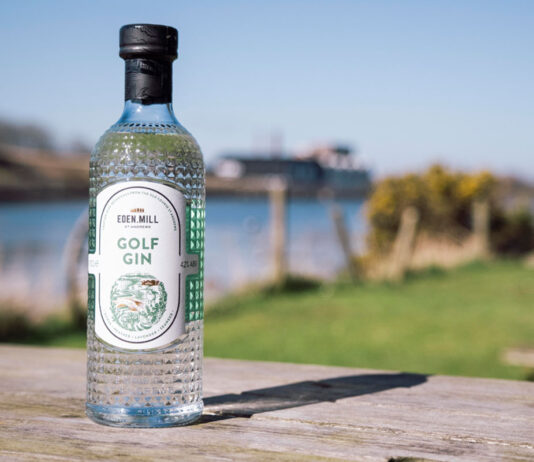 Eden Mill extends partnership with Genesis Scottish Open as Official Gin A bottle of Eden Mill Golf Gin stands on a wooden table with greenery and water in the background.