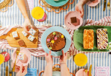 A party scene with people holding plates of cakes from the Nadiya Hussain Finsbury Food Group collection.