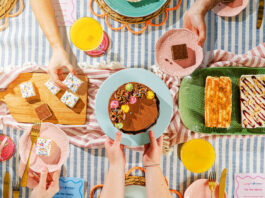 A party scene with people holding plates of cakes from the Nadiya Hussain Finsbury Food Group collection.