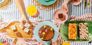 A party scene with people holding plates of cakes from the Nadiya Hussain Finsbury Food Group collection.
