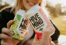 Two people clink together cans of Hive Mind Sparking Mead in a 'Cheers' action.