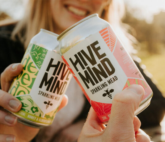 Hive Mind sparkling mead cans roll out to M&S stores Two people clink together cans of Hive Mind Sparking Mead in a 'Cheers' action.