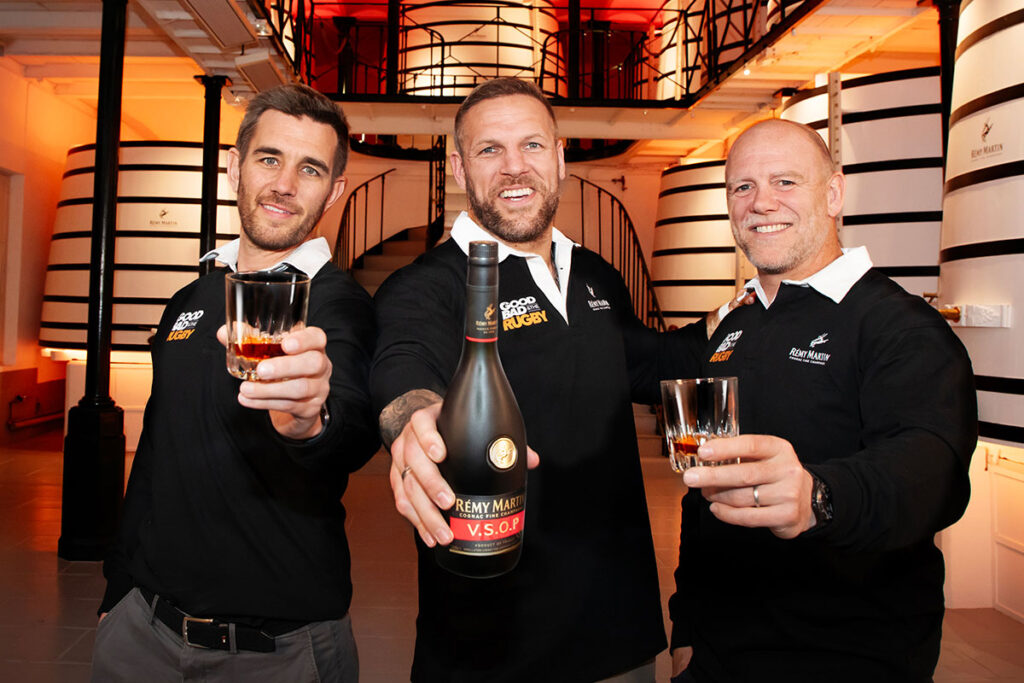 English rugby players James Haskell, Mike Tindall and broadcaster Alex Payne stand in a distillery holding glasses as Haskell holds a bottle of Rémy Martin VSOP as part of a campaign for the brand.