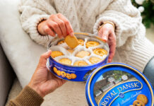 A person lifts biscuits out from a blue Royal Dansk biscuit tin.