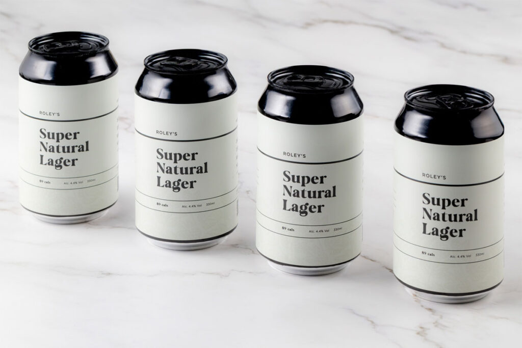 Cans of Roley's Super Natural Lager stand on a marble worktop.