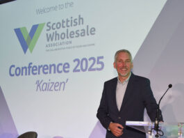 Scottish Wholesale Association unveils new logo following annual conference Colin Smith, chief executive at the Scottish Wholesale Association, stands at a podium with the 2025 redesign of the firm's logo behind him.