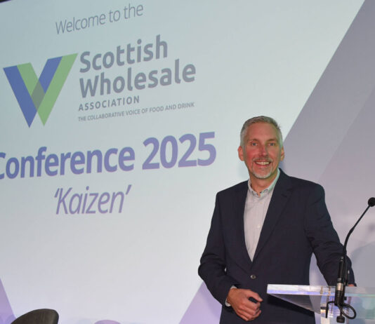 Scottish Wholesale Association unveils new logo following annual conference Colin Smith, chief executive at the Scottish Wholesale Association, stands at a podium with the 2025 redesign of the firm's logo behind him.