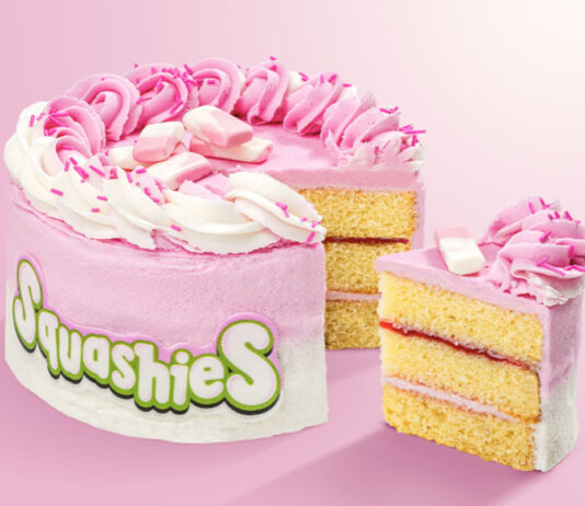 Swizzels’ first Squashies Celebration Cake heads to Tesco stores A Squashies Strawberries & Cream Celebration Cake with a slice taken out of the cake against a pink background.