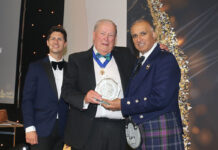 A trio of men stand on a stage at The Fed awards as the Lifetime Achievement Award is handed out.
