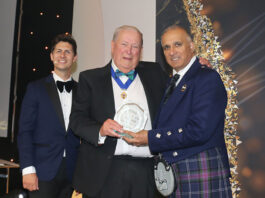 A trio of men stand on a stage at The Fed awards as the Lifetime Achievement Award is handed out.