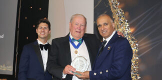 A trio of men stand on a stage at The Fed awards as the Lifetime Achievement Award is handed out.
