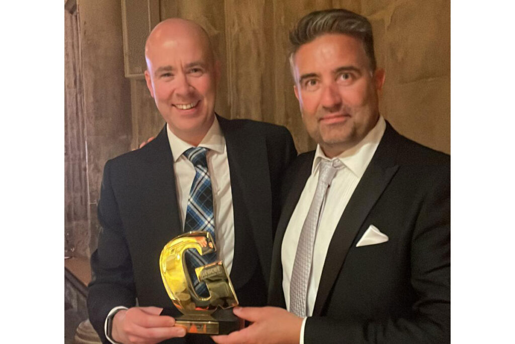 Craig Brown (left) and Chris Miller (right) stand together holding Grocer Gold award.