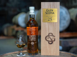 A bottle of Glen Scotia 25 Year Old stands next to its wooden box package and a nosing glass with the Glen Scotia logo on it – the bottle was gifted to King Charles III.