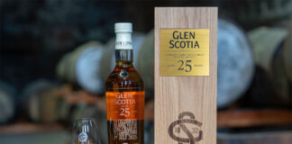 A bottle of Glen Scotia 25 Year Old stands next to its wooden box package and a nosing glass with the Glen Scotia logo on it – the bottle was gifted to King Charles III.