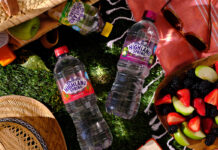 Bottles of Highland Spring flavours water at a picnic with food spilled out onto a patch of grass.
