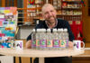 Brad Whittingham, Four Pillars LGBT+ Inclusion Advocate, sits at a table with bottles of MacB water and Four Pillars branded mugs.