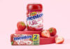 Mentos Pure Fresh Gum Strawberry tub and duo pack are standing on a red platform with cut up strawberries around them with a pink background.