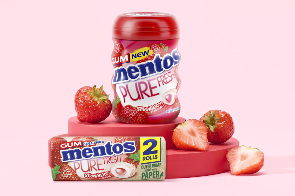 Mentos Pure Fresh Gum Strawberry tub and duo pack are standing on a red platform with cut up strawberries around them with a pink background.