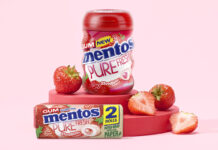 Mentos Pure Fresh Gum Strawberry tub and duo pack are standing on a red platform with cut up strawberries around them with a pink background.