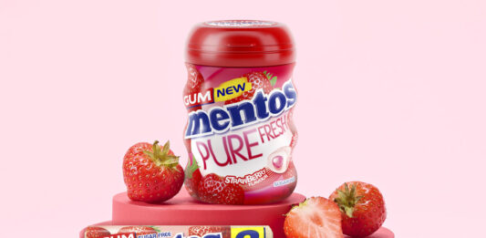 Mentos Pure Fresh Gum Strawberry tub and duo pack are standing on a red platform with cut up strawberries around them with a pink background.