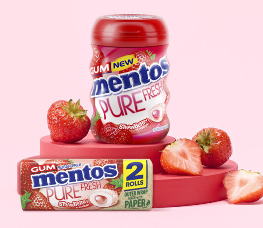 Mentos Gum rolls out a new Strawberry flavour to appeal to shoppers Mentos Pure Fresh Gum Strawberry tub and duo pack are standing on a red platform with cut up strawberries around them with a pink background.