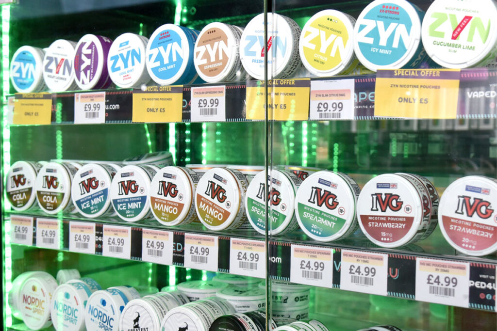 A glass cabinet filled with nicotine pouches that has been backlit with a green light.