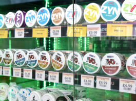 A glass cabinet filled with nicotine pouches that has been backlit with a green light.