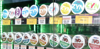 A glass cabinet filled with nicotine pouches that has been backlit with a green light.