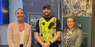 A police officer stands between two women with signage behind them for Retailers Against Crime and Go Forth Stirling.