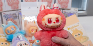 A person holds a red Labubu doll in one hand with small pieces from the doll in the other hand.
