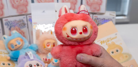 A person holds a red Labubu doll in one hand with small pieces from the doll in the other hand.