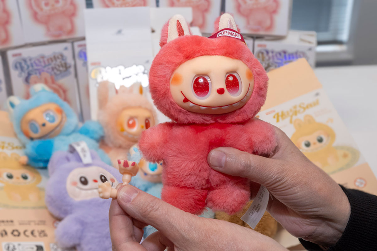 A person holds a red Labubu doll in one hand with small pieces from the doll in the other hand.
