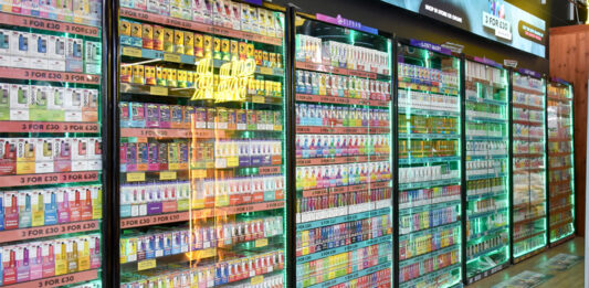UK vapers ‘blindsided’ by new duty charges Glass cabinet of vaping products lined up against a store wall.
