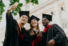 Three university graduates stand together taking a selfie.