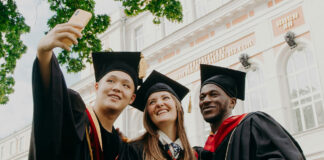 Three university graduates stand together taking a selfie.