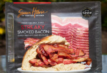 A packet of Simon Howie Smoked Streaky Bacon stands behind a bread roll filled with cooked strips of the bacon with a Three Star Great Taste Award on the packet of bacon.
