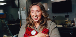 Edinburgh retailer Sophie Williams stands holding cans of Coca-Cola Zero Sugar in her arms.