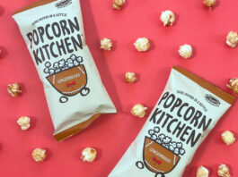 Popcorn Kitchen embraces a seasonal touch with Gingerbread Popcorn Packets of Popcorn Kitchen Gingerbread Popcorn lie against a red background with pieces of the popcorn dotted around them.