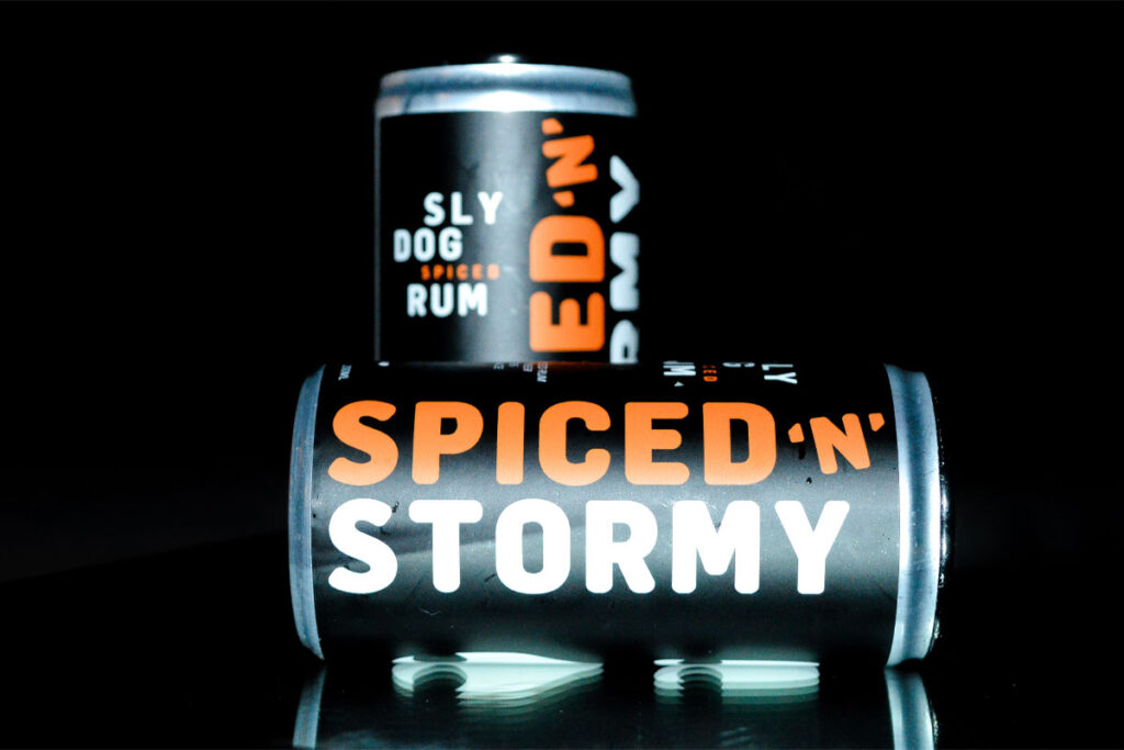 Cans of Sly Dog Rum Spiced 'n' Stormy cans against a black background.