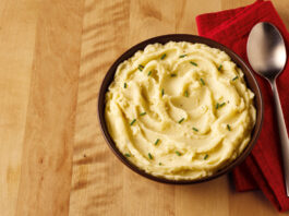 Albert Bartlett teams up with Mexicana and Applewood on new cheesy mash products A bowl of mashed potato sits on a table with a red napkin next to it and a spoon on top of the napkin.