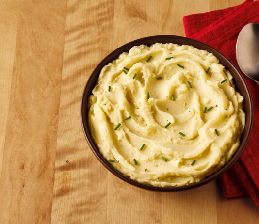 Albert Bartlett teams up with Mexicana and Applewood on new cheesy mash products A bowl of mashed potato sits on a table with a red napkin next to it and a spoon on top of the napkin.