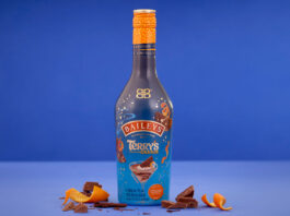 Baileys teams up with Terry’s Chocolate Orange for indulgent Christmas treat A bottle of Baileys Terry's Chocolate Orange limited edition flavour stands in front of a blue background with orange peel and pieces of chocolate around the bottle.