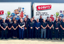 Allwyn strengthens support with Bobby’s partnership A group of representatives from food supplier Bobby's stand in front of two Bobby's branded vans.